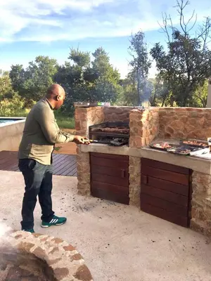 a man standing in front of an outdoor grill at Kuwisa Lodge in Bela-Bela
