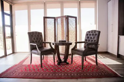 two chairs and a table in a room with windows at Kuwisa Lodge in Bela-Bela