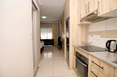 a kitchen with wooden cabinets and a counter top at Menlyn Maine Spacious Cottage in Pretoria
