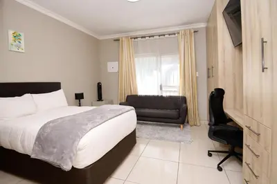 a bedroom with a bed and a chair and a couch at Menlyn Maine Spacious Cottage in Pretoria