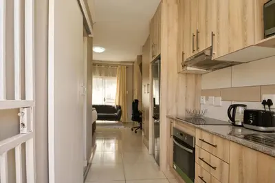 a kitchen with wooden cabinets and a counter top at Menlyn Maine Spacious Cottage in Pretoria