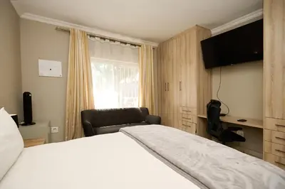 a hotel room with a bed and a chair at Menlyn Maine Spacious Cottage in Pretoria