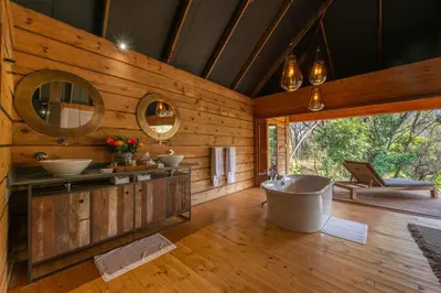 a bathroom with a tub and two sinks and a mirror at Summerfields Rose Retreat and Spa in Hazyview