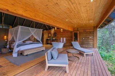 a bedroom with a bed and a tub on a wooden deck at Summerfields Rose Retreat and Spa in Hazyview
