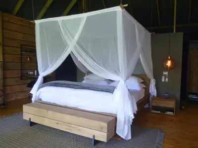 a bedroom with a canopy bed with a wooden bed frame at Summerfields Rose Retreat and Spa in Hazyview