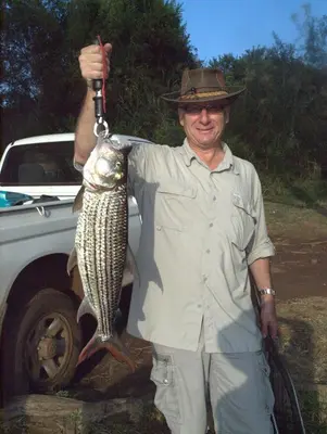a man holding a fish in his hand at Needles Lodge in Marloth Park