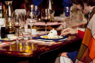 a woman eating food at a table with wine glasses at Needles Lodge in Marloth Park