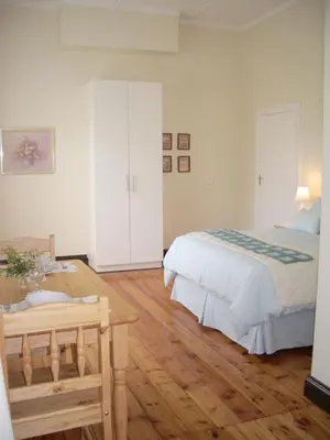 a bedroom with a bed and a wooden floor at Dee's BnB in Pretoria