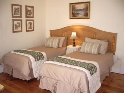 two beds in a hotel room with a lamp on a table at Dee's BnB in Pretoria