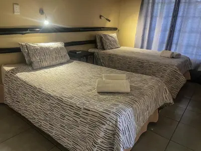 two beds in a hotel room with towels on them at Leribisi Lodge in Tierpoort