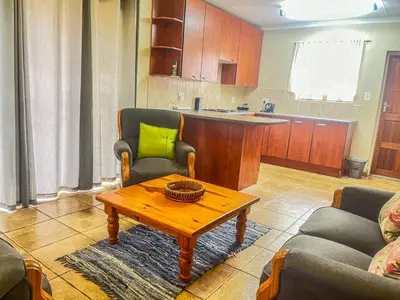 a living room with a table and a kitchen at Leribisi Lodge in Tierpoort