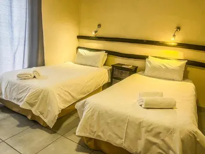 two beds in a hotel room with towels on them at Leribisi Lodge in Tierpoort