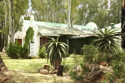 a white house with a green roof and trees at The Highveld Cape Inn in Pretoria