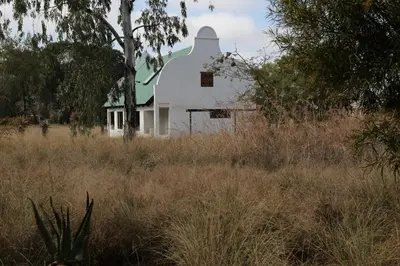a white house with a green roof in a field at The Highveld Cape Inn in Pretoria