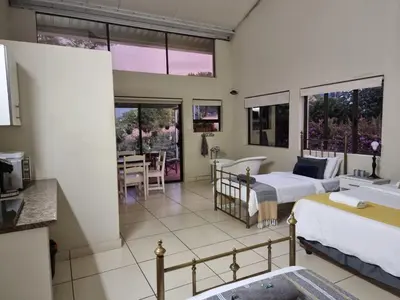 a hotel room with two beds and a bathroom at Tzaneen White House Lodge in Tzaneen
