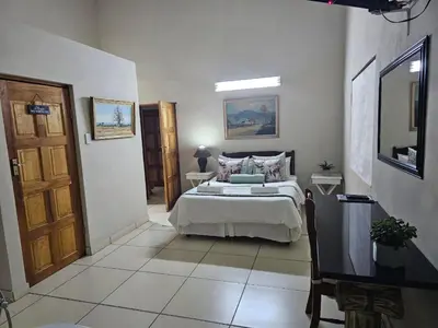 a bedroom with a bed and a television in it at Tzaneen White House Lodge in Tzaneen