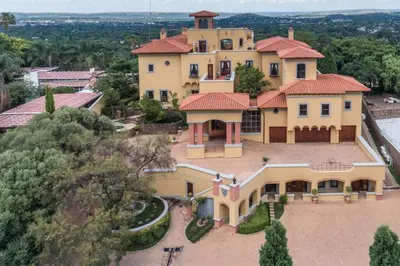 an aerial view of a large yellow house with red roof at Castello Di Monte in Pretoria