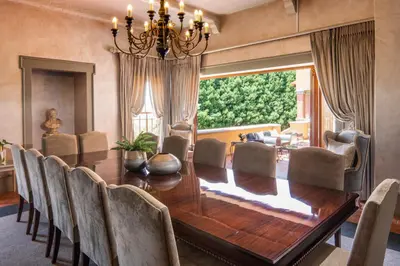 a dining room with a wooden table and chairs at Castello Di Monte in Pretoria
