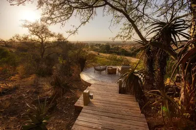 a wooden walkway with a table and chairs on it at Klaserie Drift Misava in Klaserie Private Nature Reserve