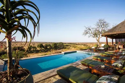 a swimming pool with chaise lounge chairs and a resort at Klaserie Drift Misava in Klaserie Private Nature Reserve