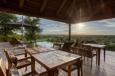 a deck with tables and chairs and a pool at Klaserie Drift Misava in Klaserie Private Nature Reserve