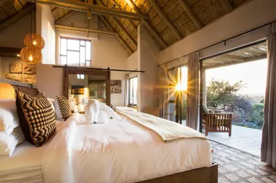 a bedroom with a large bed and a large window at Klaserie Drift Misava in Klaserie Private Nature Reserve