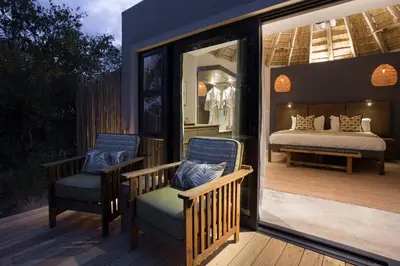 a room with a bed and two chairs on a deck at Klaserie Drift Misava in Klaserie Private Nature Reserve