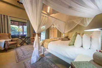 a bedroom with a canopy bed with curtains at Kambaku Safari Lodge in Timbavati Game Reserve