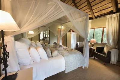 a bedroom with a canopy bed with white pillows at Kambaku Safari Lodge in Timbavati Game Reserve