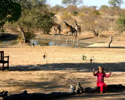 a little girl standing in front of a group of giraffes at Kambaku Safari Lodge in Timbavati Game Reserve