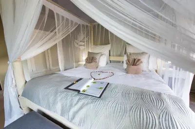 a white bed with a tray of food on it at Kambaku Safari Lodge in Timbavati Game Reserve