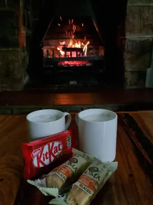 a table with two cups and some food and a fireplace at Alm-Ü in Dullstroom