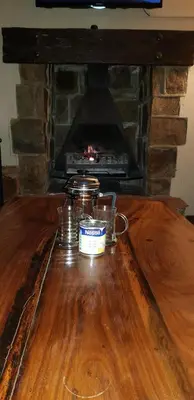 a wooden table in front of a stone fireplace at Alm-Ü in Dullstroom