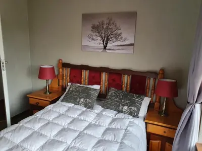 a bedroom with a bed with two lamps and a tree at Alm-Ü in Dullstroom