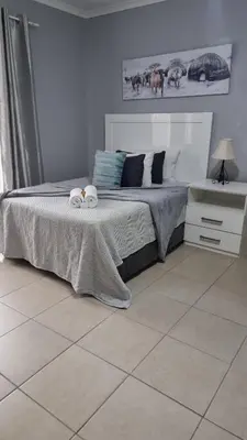 a bedroom with a bed with two towels on it at Stay at Home Airport Lodge in Kempton Park