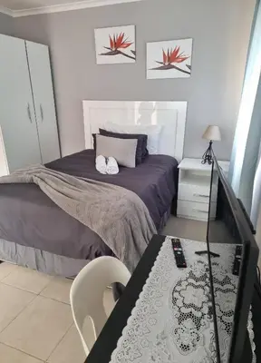 a small bedroom with a bed and a table at Stay at Home Airport Lodge in Kempton Park