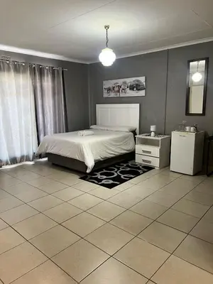 a bedroom with a bed and a tiled floor at Stay at Home Airport Lodge in Kempton Park