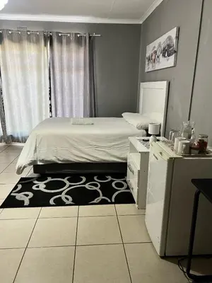 a bedroom with a bed and a black and white rug at Stay at Home Airport Lodge in Kempton Park