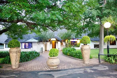 a brick walkway in front of a house with two large vases at Lalapanzi Hotel & Conference Centre in Bandelierkop