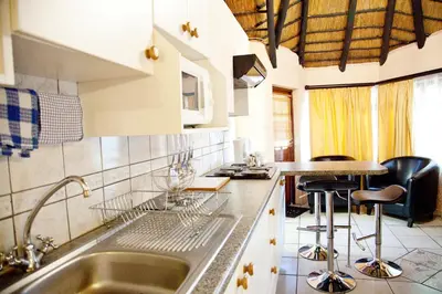 a kitchen with a sink and a counter with stools at Lalapanzi Hotel & Conference Centre in Bandelierkop