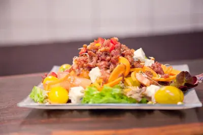a plate of salad with meat and vegetables on a table at Lalapanzi Hotel & Conference Centre in Bandelierkop