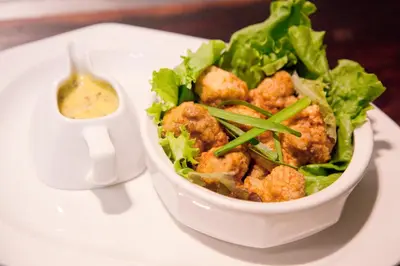 a white bowl of food on a plate with a salad at Lalapanzi Hotel & Conference Centre in Bandelierkop