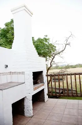 a white brick fireplace sitting next to a wooden fence at Lalapanzi Hotel & Conference Centre in Bandelierkop