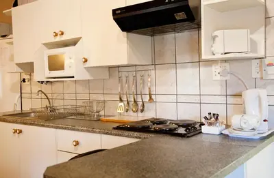 a kitchen with white cabinets and a counter top at Lalapanzi Hotel & Conference Centre in Bandelierkop