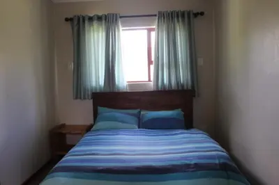 a bedroom with a bed and a window with blue pillows at Misty Cottage in Dullstroom