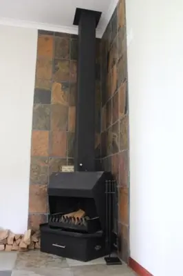 a fireplace in a room with a brick wall at Misty Cottage in Dullstroom