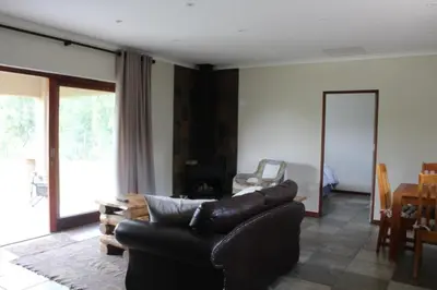 a living room with a leather couch and a table at Misty Cottage in Dullstroom