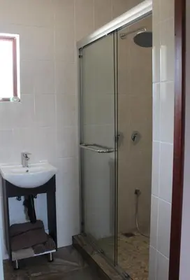 a bathroom with a glass shower and a sink at Misty Cottage in Dullstroom