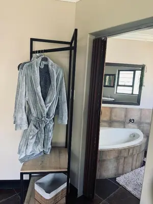 a bathroom with a bath tub and a robe at Annie's Place in Kempton Park