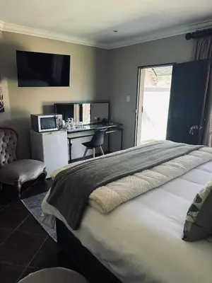 a bedroom with a large bed with a desk and a chair at Annie's Place in Kempton Park
